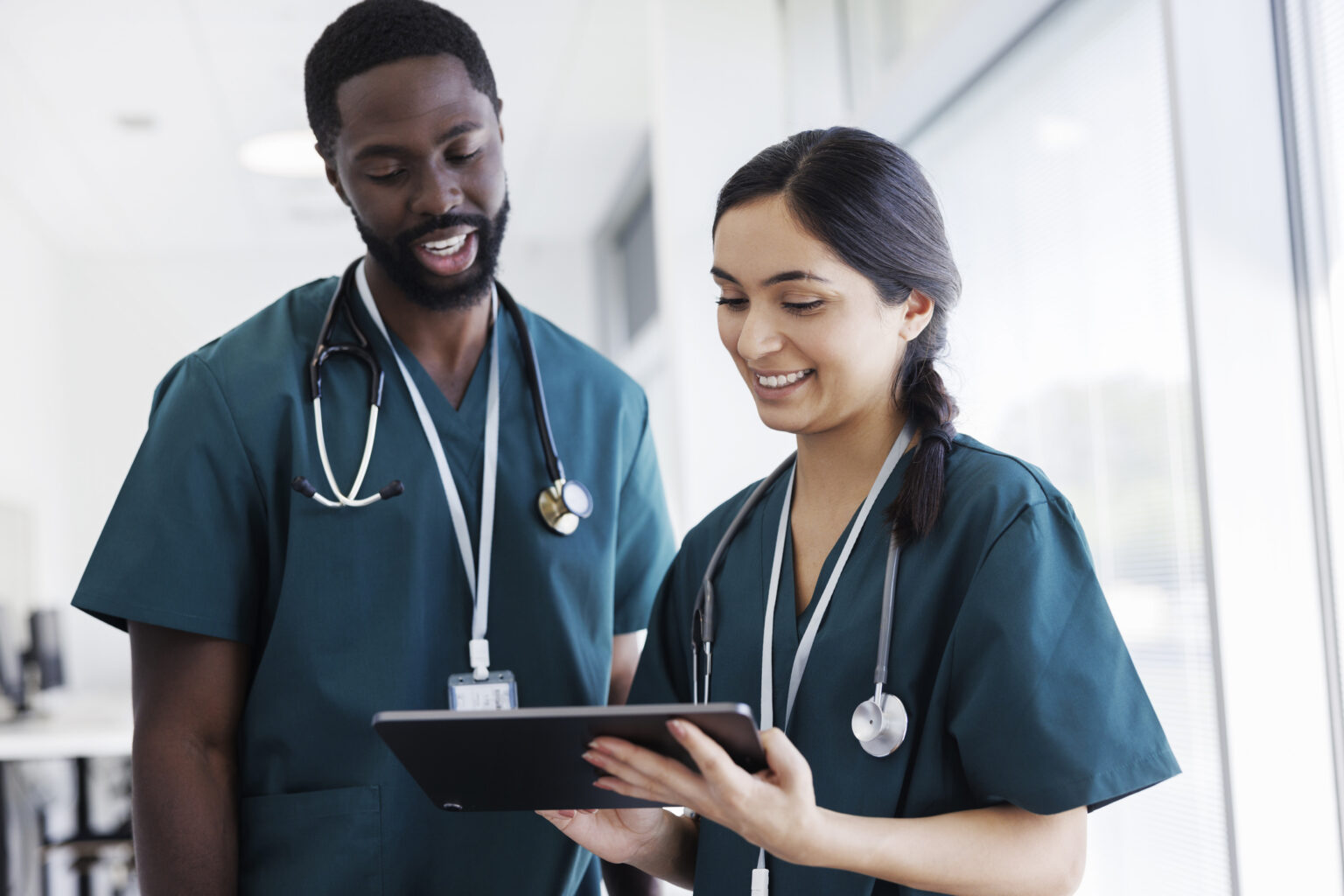 Two care providers reviewing a patient record on a tablet