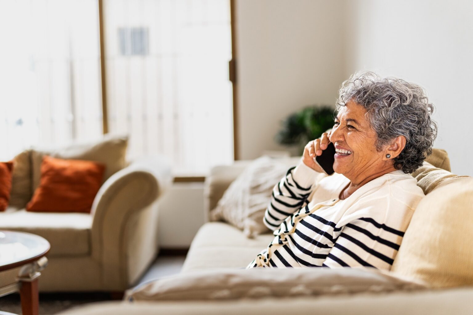 Smiling older woman talking on the phone at home